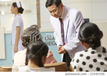 a doctor is standing, listening and answering his patients 33595590