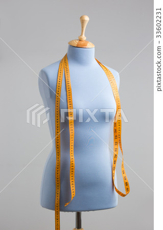 Blue tailor dummy with measuring tape alongside Blue tailor dummy with measuring tape alongside 33602231
