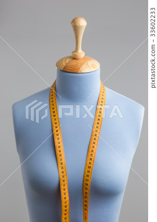Blue tailor dummy with measuring tape alongside Blue tailor dummy with measuring tape alongside 33602233