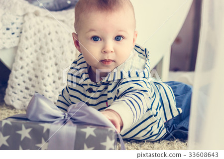 Baby boy is reaching to his present Baby boy is reaching to his present 33608643
