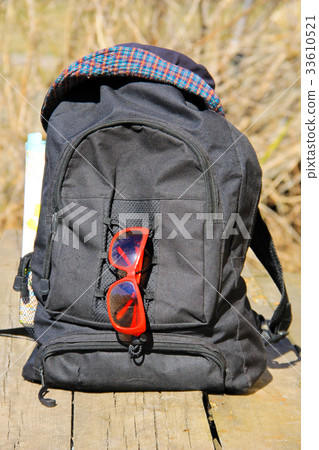 Backpack with hat, red sunglasses and map 33610521