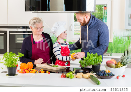 Dad, grandma and kid cooking together in kitchen 33611825