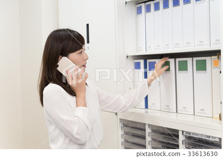 Female employee who takes out files while calling Female employee who takes out files while calling 33613630