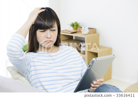 Young woman playing tablet on the couch Young woman playing tablet on the couch 33616411