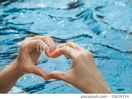 Heart from hands on swimming pool Heart from hands on swimming pool 33619154