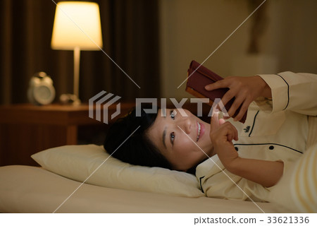 Young woman looking at smartphone in bed 33621336