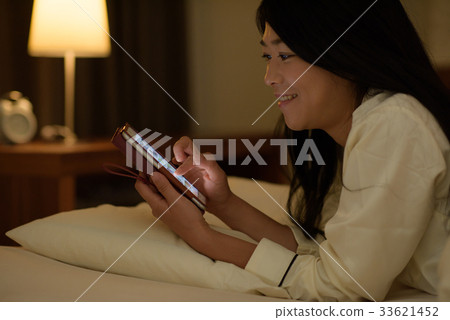 Young woman looking at smartphone in bed 33621452