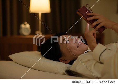Young woman looking at smartphone in bed 33621506