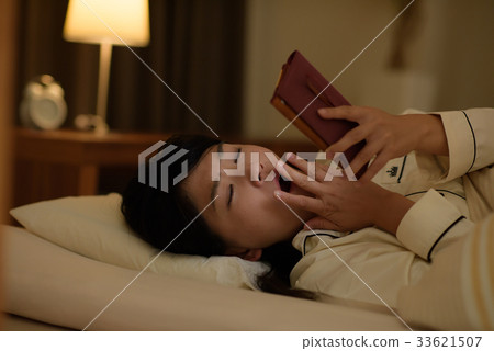 Young woman looking at smartphone in bed Young woman looking at smartphone in bed 33621507