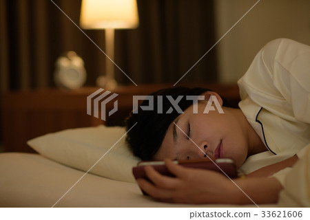 一名婦女在床上的看一個智能手機 33621606