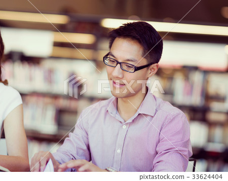 Happy male student holding books at the library Happy male student holding books at the library 33624404