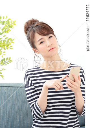 A woman relaxing on a sofa · Smartphone 33624751