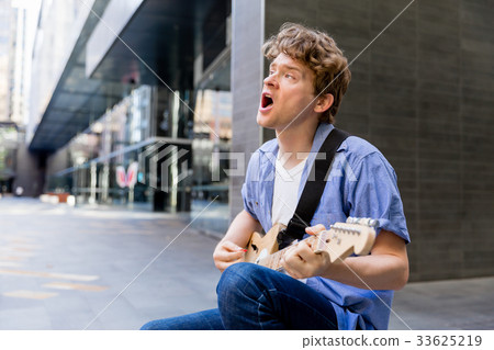 Young musician with guitar in city Young musician with guitar in city 33625219