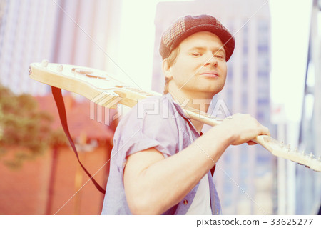 Young musician with guitar in city Young musician with guitar in city 33625277