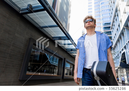 Young musician with guitar in city Young musician with guitar in city 33625286