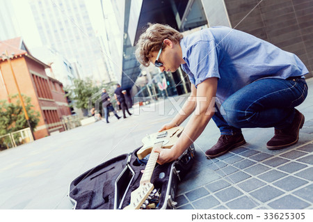 Young musician with guitar in city Young musician with guitar in city 33625305