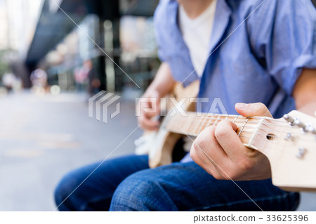 Young musician with guitar in city Young musician with guitar in city 33625396
