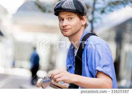 Young musician with guitar in city Young musician with guitar in city 33625397