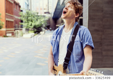 Young musician with guitar in city 33625499