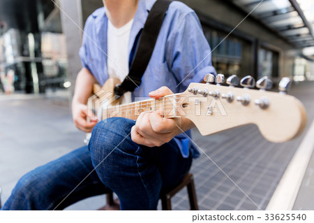 Young musician with guitar in city Young musician with guitar in city 33625540