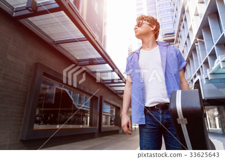 Young musician with guitar in city Young musician with guitar in city 33625643
