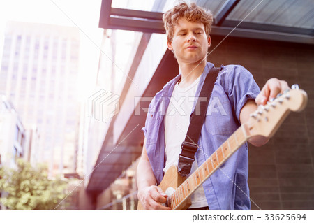 Young musician with guitar in city Young musician with guitar in city 33625694