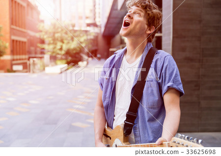 Young musician with guitar in city Young musician with guitar in city 33625698