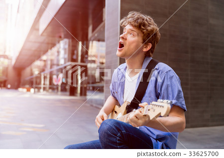 Young musician with guitar in city Young musician with guitar in city 33625700