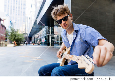 Young musician with guitar in city Young musician with guitar in city 33625910
