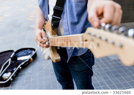 Young musician with guitar in city 33625980