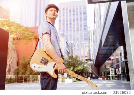 Young musician with guitar in city Young musician with guitar in city 33626023