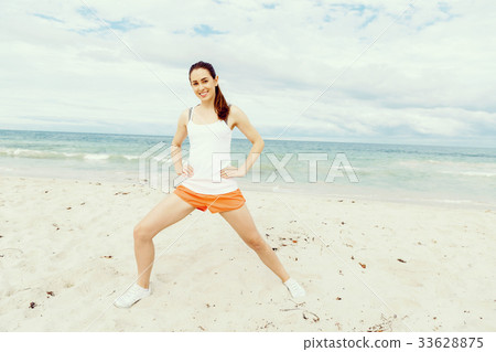 Young woman training on beach outside 33628875