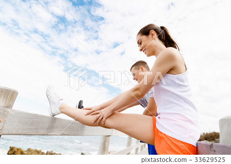 Runners. Young couple exercising and stertching on beach Runners. Young couple exercising and stertching on beach 33629525