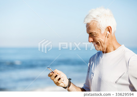 Male runner with his mobile smart phone standing outdoors 33629594