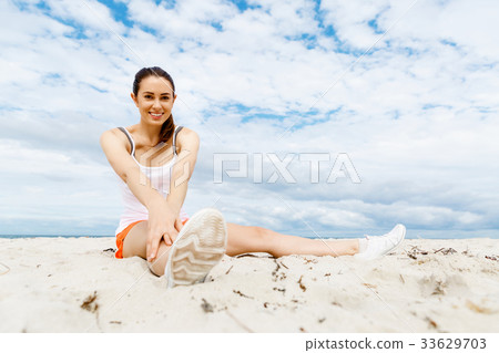 Young woman training on beach outside 33629703