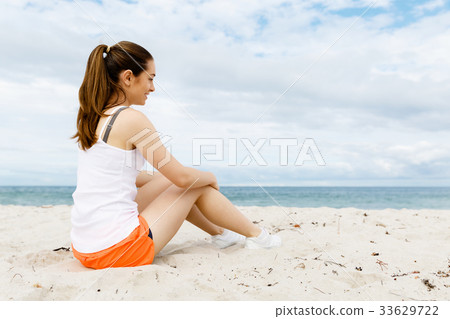 Young woman in sports wear sitting at the beach 33629722