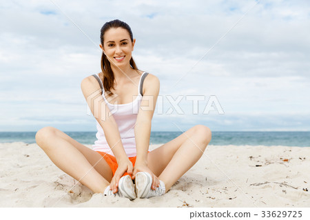 Young woman training on beach outside 33629725