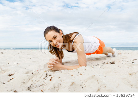 Young woman training on beach outside 33629754