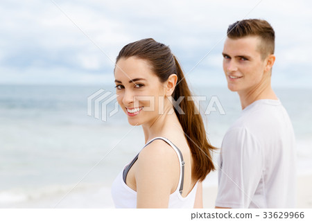 Young couple looking thoughtful while standing next to each other on beach Young couple looking thoughtful while standing next to each other on beach 33629966