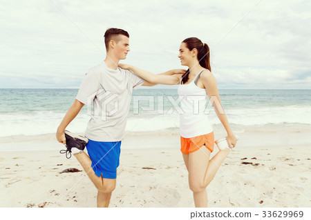 Runners. Young couple exercising and stertching on beach 33629969