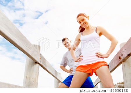 Runners. Young couple exercising and stertching on beach 33630188