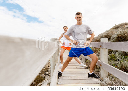 Runners. Young couple exercising and stertching on beach Runners. Young couple exercising and stertching on beach 33630190