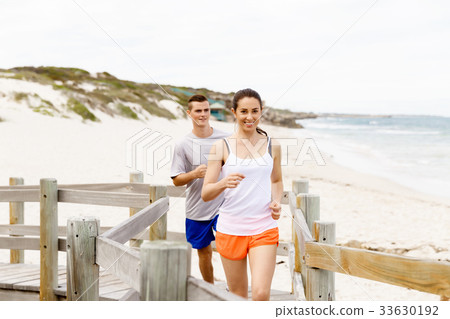 Runners. Young couple running on beach 33630192