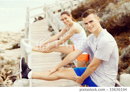 Runners. Young couple exercising and stertching on beach Runners. Young couple exercising and stertching on beach 33630194
