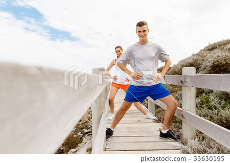 Runners. Young couple exercising and stertching on beach Runners. Young couple exercising and stertching on beach 33630195