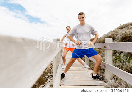 Runners. Young couple exercising and stertching on beach Runners. Young couple exercising and stertching on beach 33630196