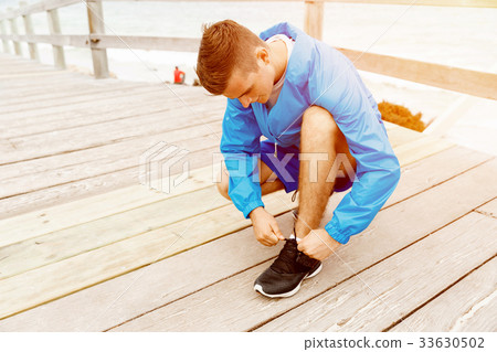 Runner laces his shoes and prepares to jogging Runner laces his shoes and prepares to jogging 33630502