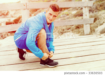 Runner laces his shoes and prepares to jogging 33630503