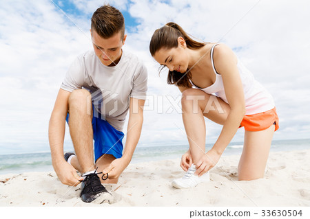 Runners lace their shoes and prepare to jogging 33630504