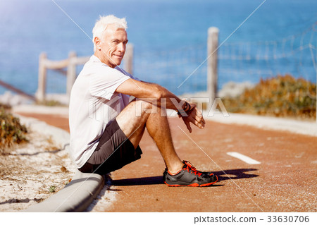 Man in sports wear sitting at the beach Man in sports wear sitting at the beach 33630706
